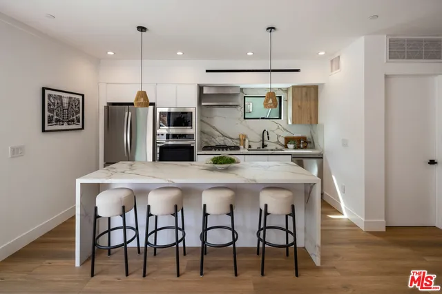 a kitchen with stainless steel appliances kitchen island a refrigerator and microwave