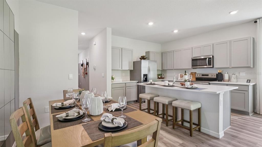 32507 Welling Blade Loop Wesley Chapel, FL 33545 - Photo 10 of 39 a kitchen with stainless steel appliances stove refrigerator dining table and chairs