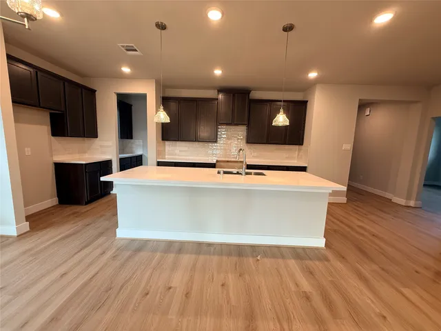 a view of kitchen with stainless steel appliances granite countertop a sink a microwave and wooden floor