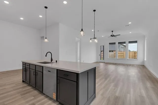 a kitchen with a sink chandelier and wooden floor