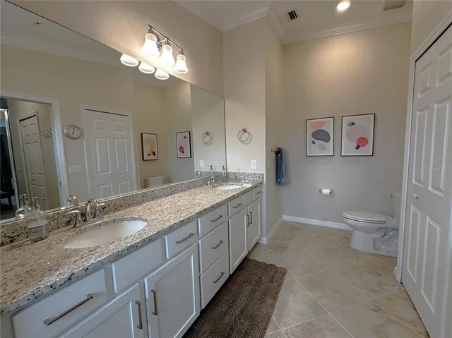 a spacious bathroom with a granite countertop sink a toilet and a large mirror