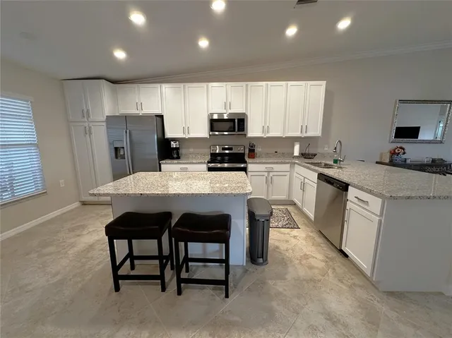a kitchen with a sink a stove a refrigerator cabinets and a dining table