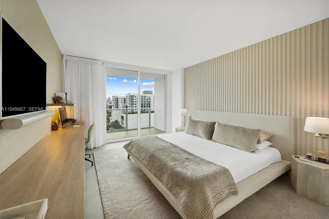 a spacious bedroom with a bed and a flat tv screen on the dresser