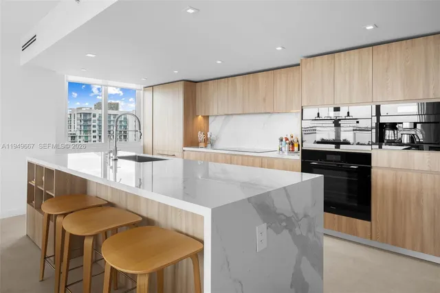 a kitchen with stainless steel appliances granite countertop a sink a stove a refrigerator cabinets and chairs