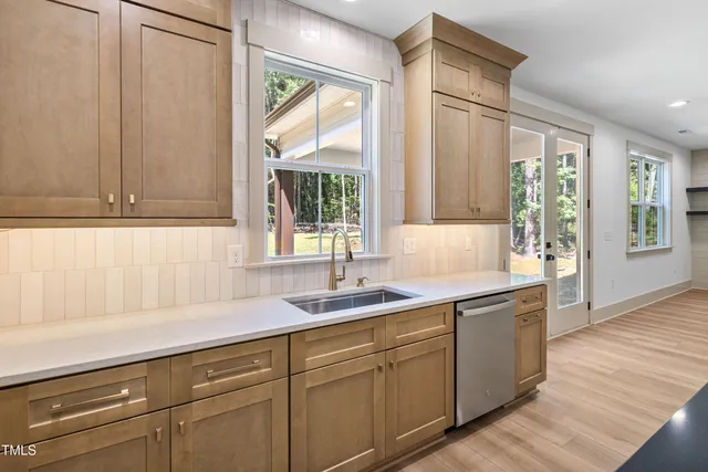 a kitchen with granite countertop a sink and white cabinets with wooden floor