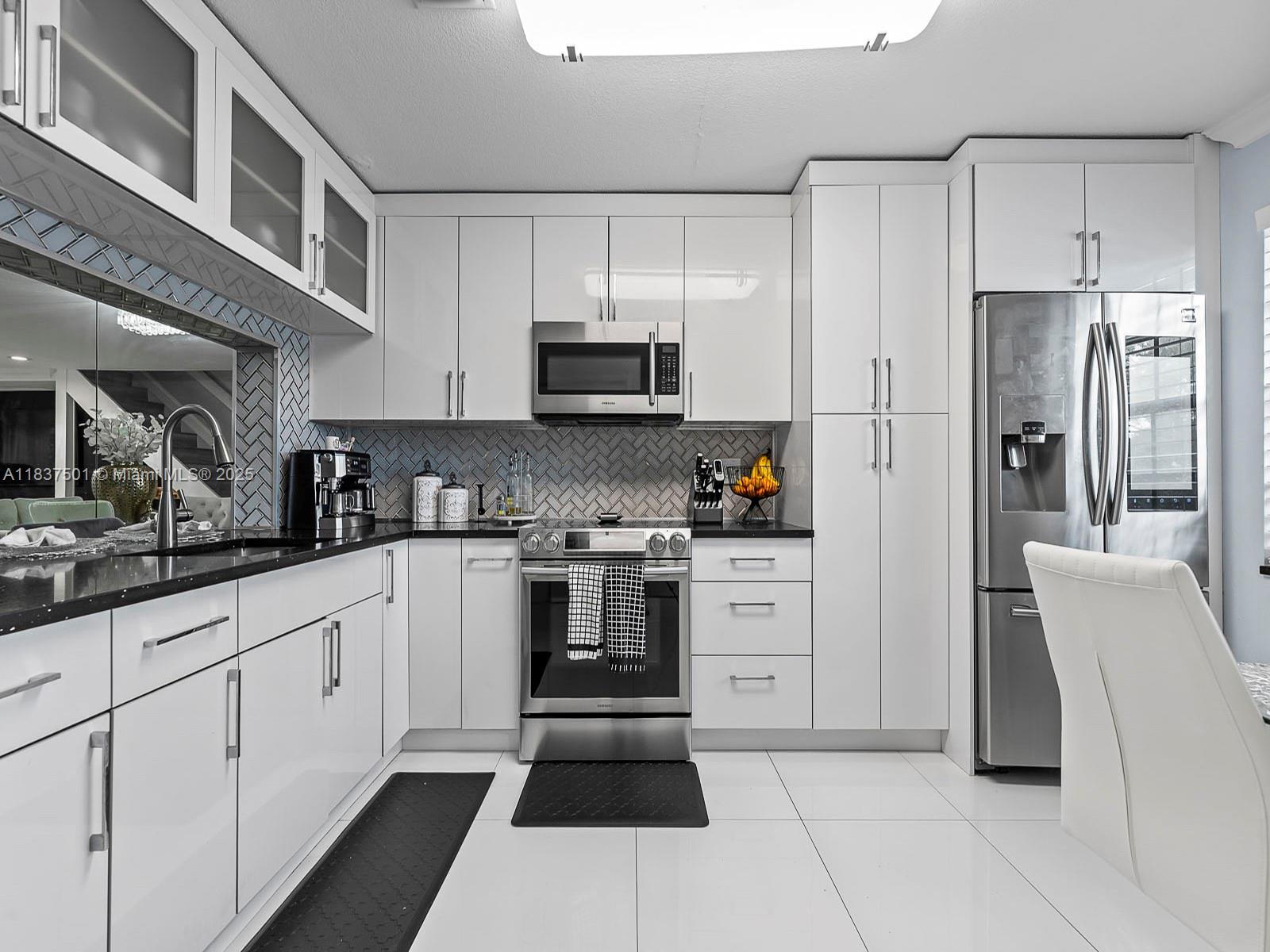 10942 West Sample Road, Unit E1 Coral Springs, FL 33065 - Photo 11 of 32 a kitchen with stainless steel appliances and white cabinets