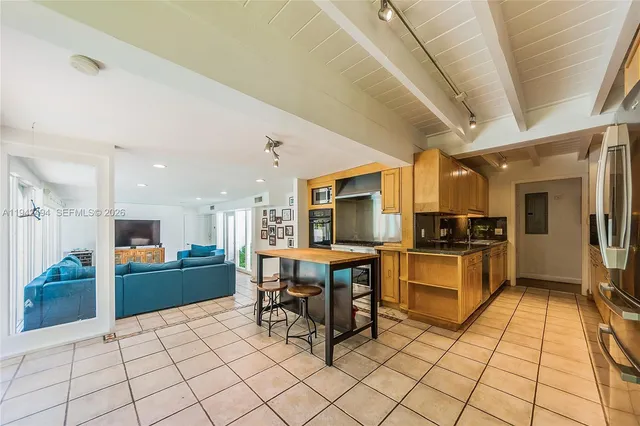 a kitchen with stainless steel appliances kitchen island granite countertop a refrigerator a stove a sink a dining table and chairs with wooden floor