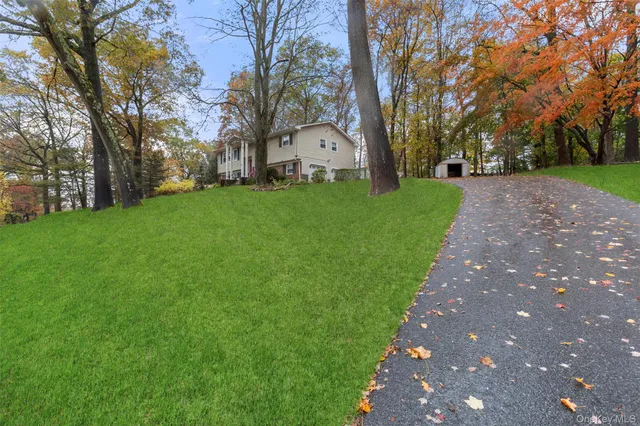 a view of a white house with a big yard and large trees