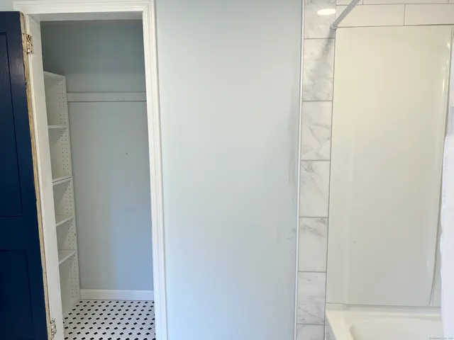 a walk in closet with wooden floor