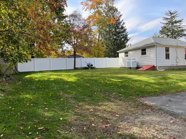 a view of a house with a yard and a large tree