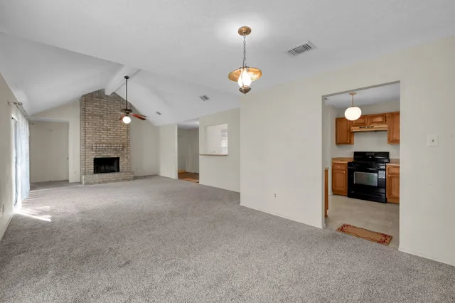 wooden floor in an empty room with a fireplace and a window