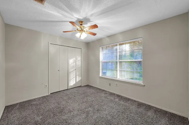 an empty room with windows and fan
