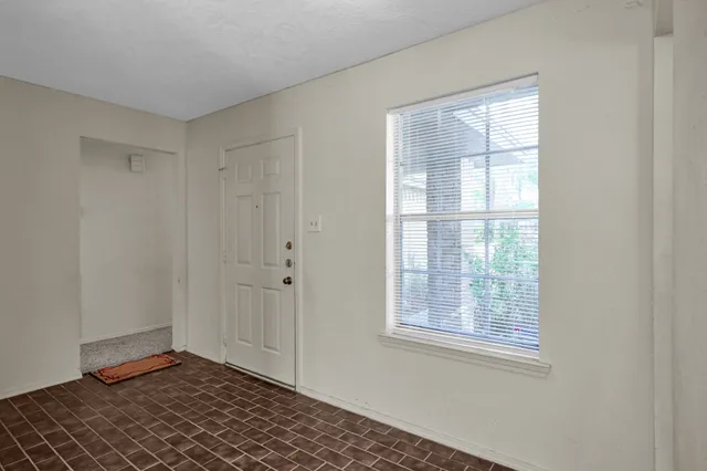 a view of an empty room with window and closet area