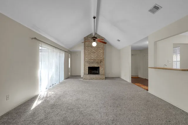 a view of an empty room with a fireplace and a window