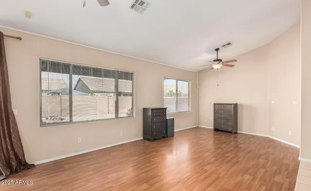 an empty room with wooden floor and windows