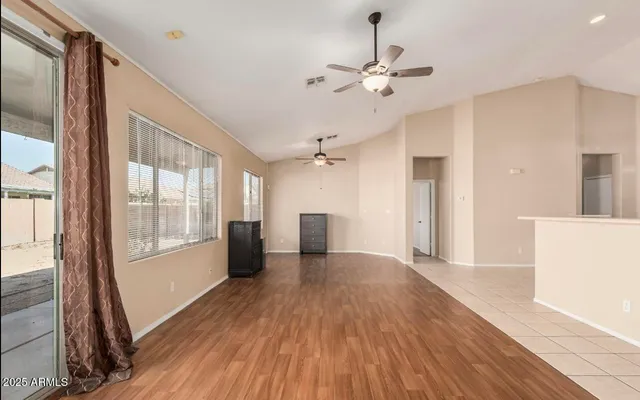 a view of a room with wooden floor fan and windows