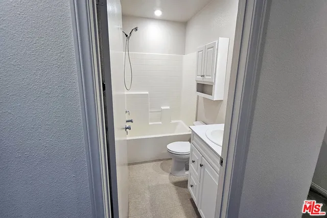 a bathroom with a granite countertop toilet a sink and a mirror