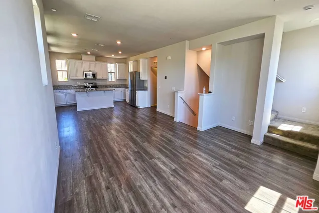 a view of kitchen with kitchen island wooden floor and refrigerator