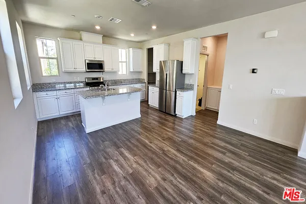 a kitchen with stainless steel appliances a refrigerator and wooden floor