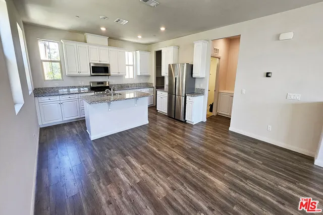 a kitchen with stainless steel appliances a refrigerator and wooden floor