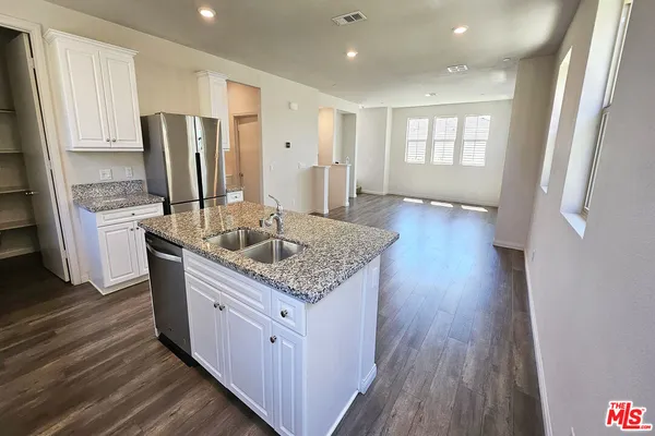 a kitchen with stainless steel appliances granite countertop a sink dishwasher a refrigerator and wooden floor