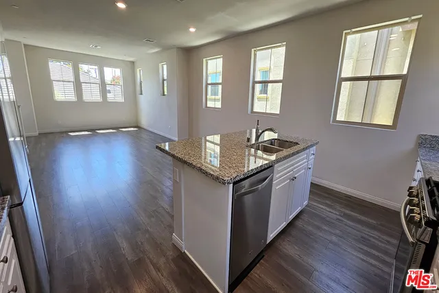 a kitchen with granite countertop a sink and wooden floor