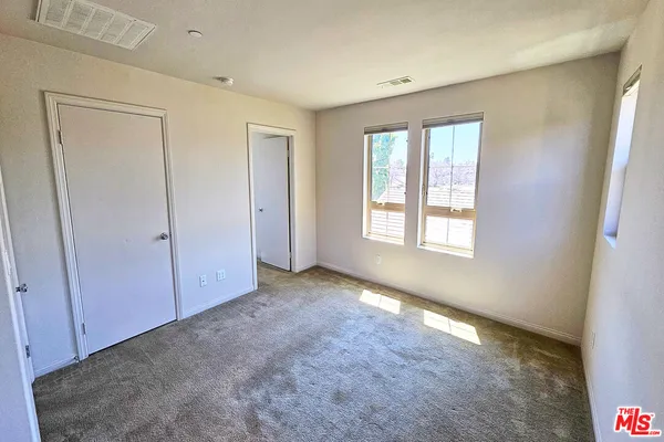 a view of an empty room with window and closet area