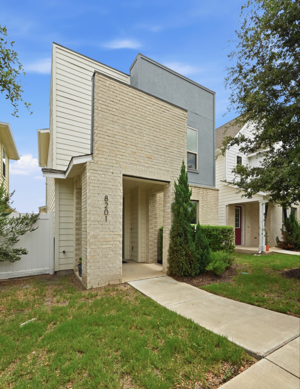 8201 Frida Bend Austin, TX 78744 - Photo 3 of 29 Modern facade showcasing brick and siding, complemented by verdant landscaping.
