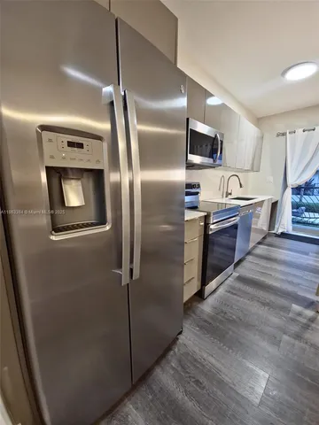 a kitchen with stainless steel appliances granite countertop a refrigerator a stove and a sink with wooden floor