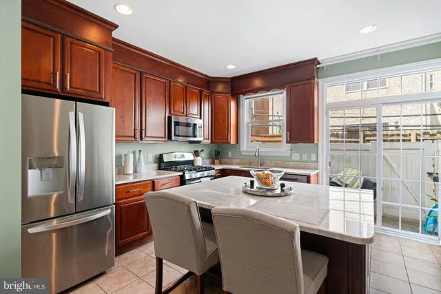 a kitchen with stainless steel appliances a refrigerator a sink a stove a table and chairs