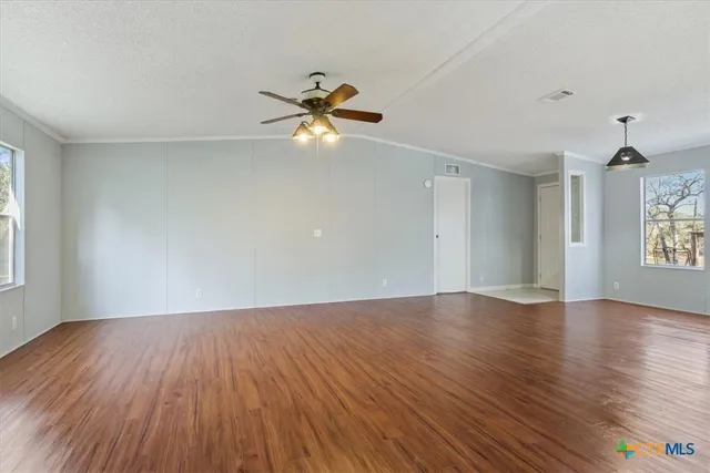 an empty room with wooden floor fan and windows