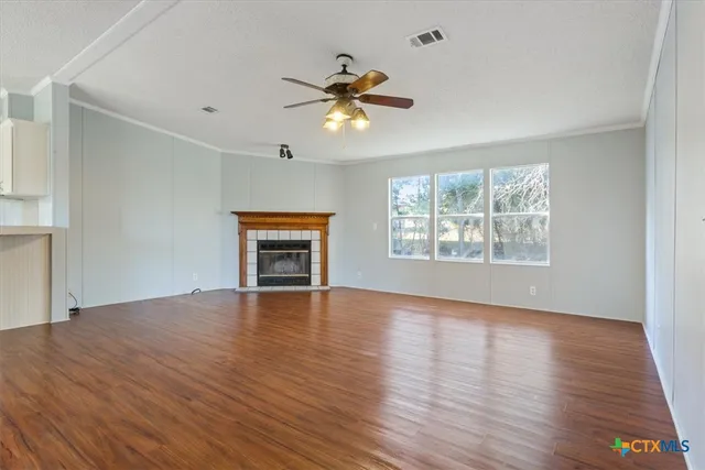 a view of an empty room with window and wooden floor