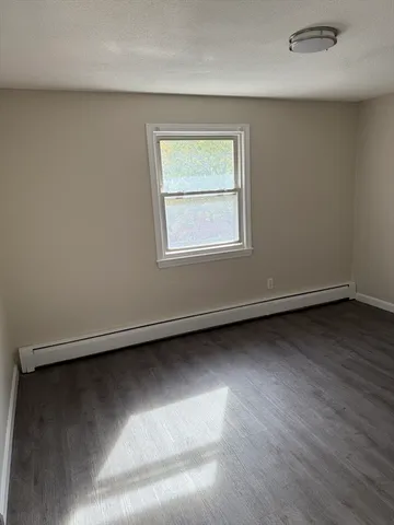 an empty room with wooden floor and a window