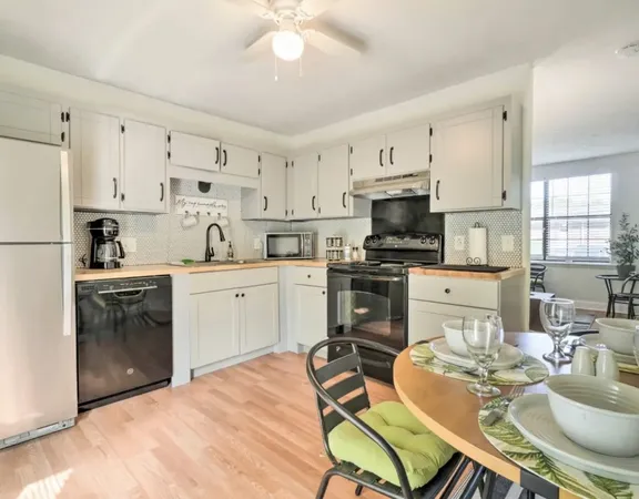 a kitchen with stainless steel appliances kitchen island granite countertop a sink dishwasher a stove a refrigerator with a dining table and chairs