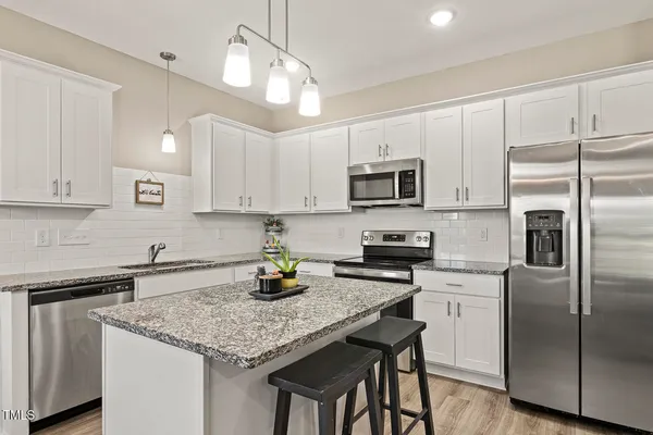 a kitchen with kitchen island granite countertop a sink a counter space stainless steel appliances and cabinets