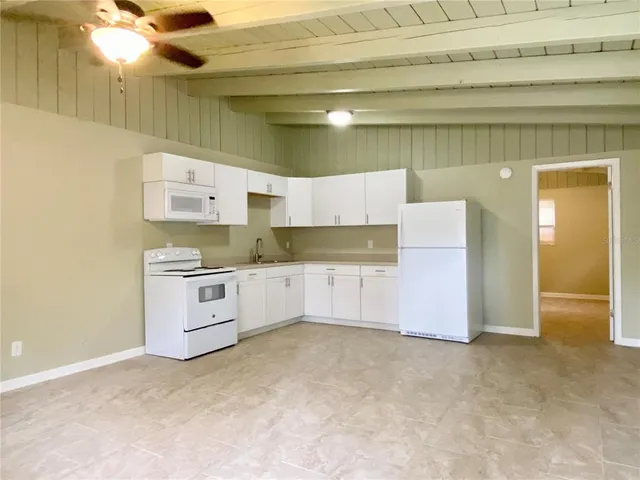 a large white kitchen with granite countertop a sink
