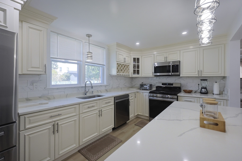 1245 North High Street Fall River, MA 02720 - Photo 7 of 28 a kitchen with kitchen island granite countertop white cabinets a sink a window and stainless steel appliances