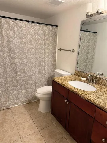 a bathroom with a granite countertop sink and a toilet