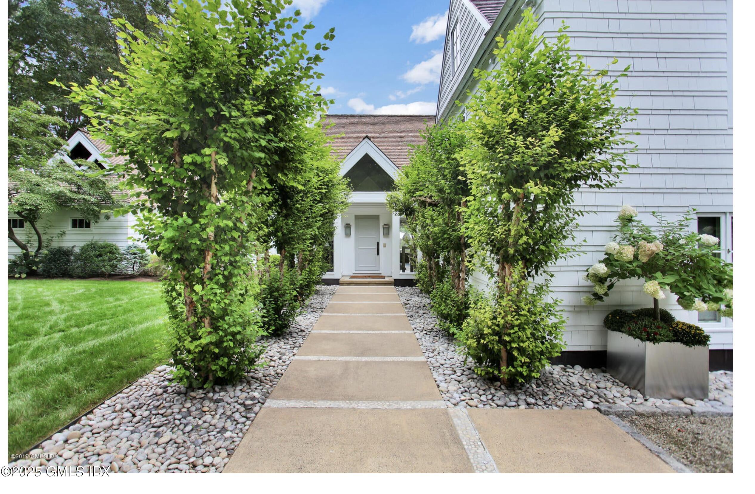 a view of house with a yard and potted plants