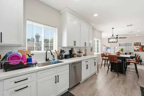 a kitchen with white cabinets sink dining table and chairs