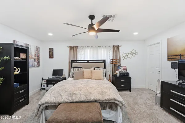 a bedroom with a bed and a flat tv screen on dresser