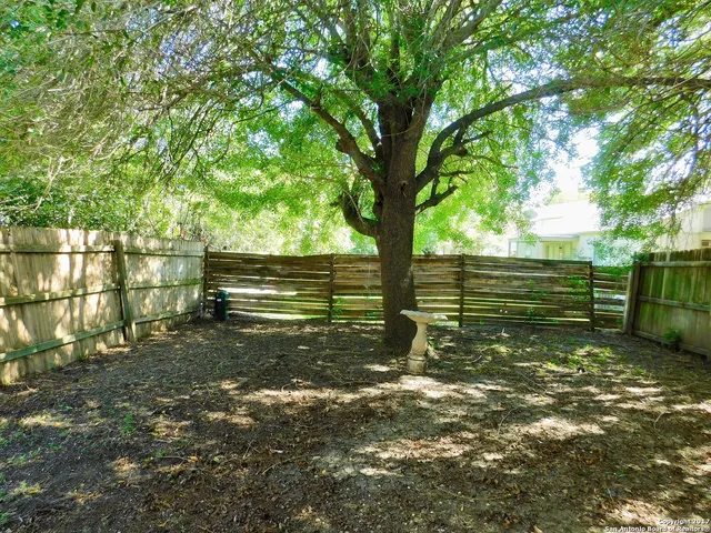 a view of a yard with wooden fence