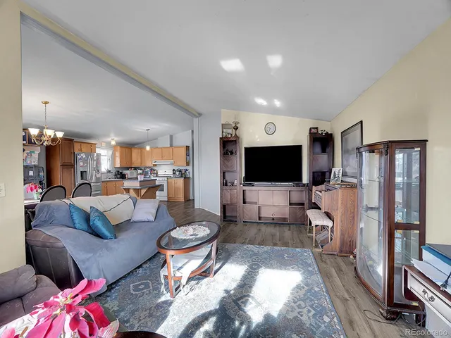 a kitchen with stainless steel appliances granite countertop a stove top oven a sink a dining table and chairs with wooden floor