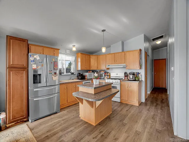 a large kitchen with stainless steel appliances kitchen island a stove a refrigerator a sink and a cabinets