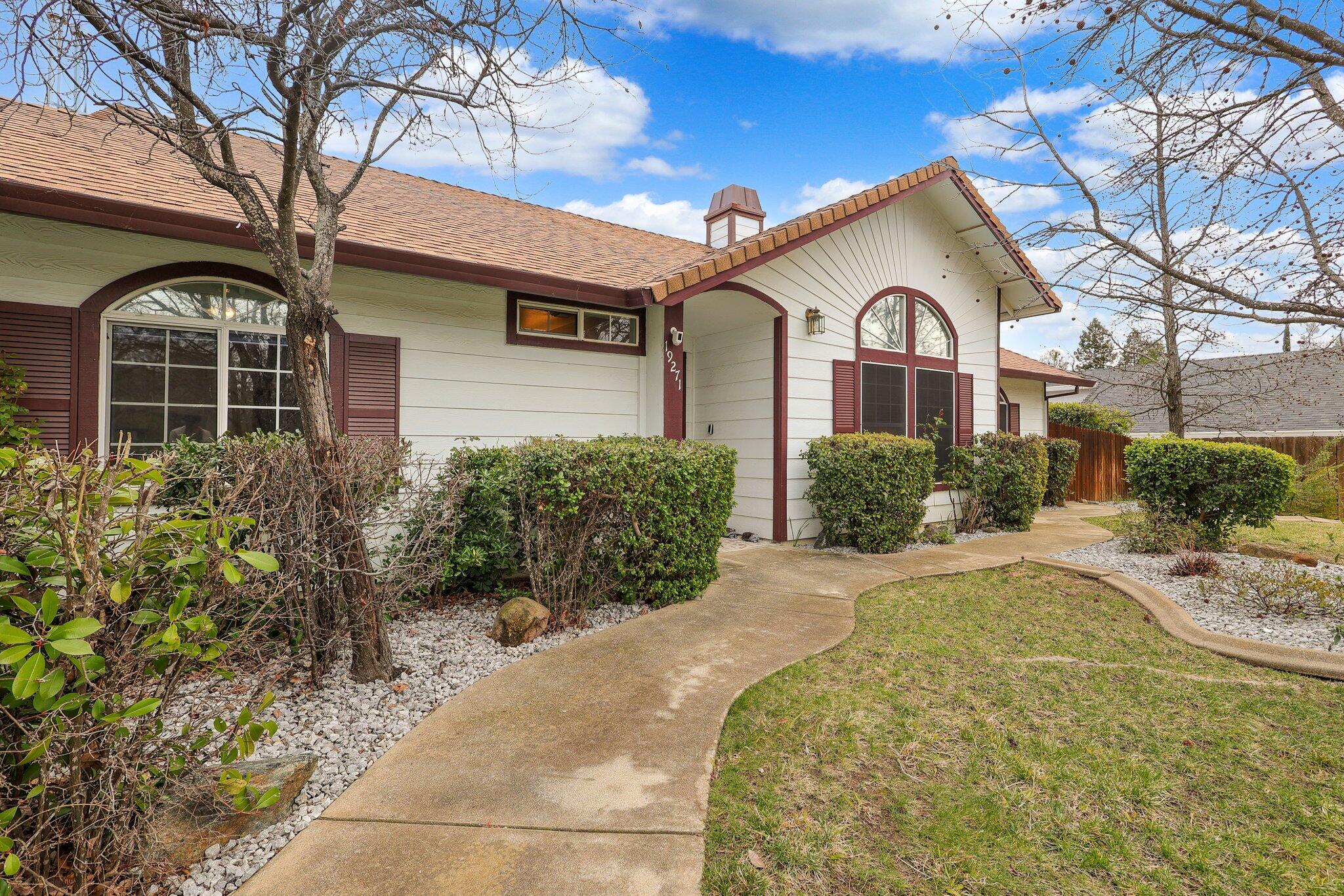 19271 Lexington Lane Redding, CA 96003 - Photo 4 of 39 a view of a white house with a yard and flower plants