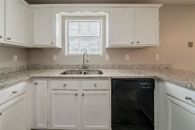 a kitchen with granite countertop white cabinets and a sink