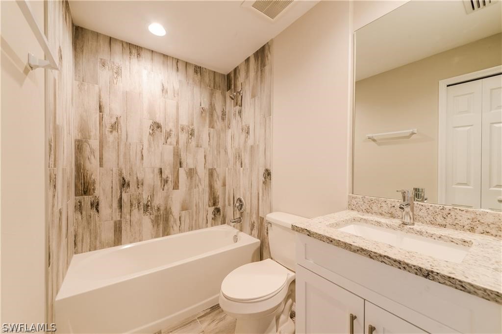 8422 Cardinal Road Fort Myers, FL 33967 - Photo 13 of 15 a bathroom with a granite countertop sink a toilet and a bathtub
