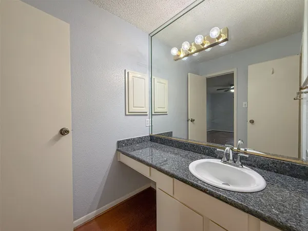 a bathroom with a granite countertop sink a light fixture and a mirror