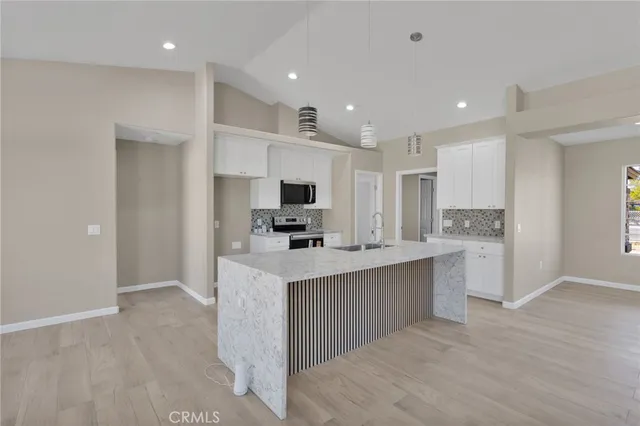 a kitchen with kitchen island a sink stainless steel appliances and cabinets
