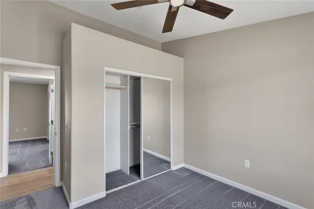 an empty room with wooden floor a ceiling fan and windows